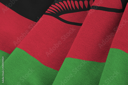 Malawi flag with big folds waving close up under the studio light indoors. The official symbols and colors in banner photo