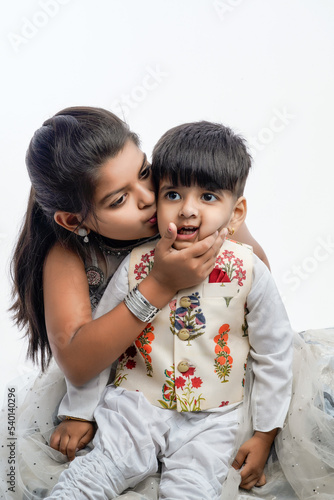 Cute little Indian asian siblings standing and embracing each other in white clothes ethnic standing against white background.