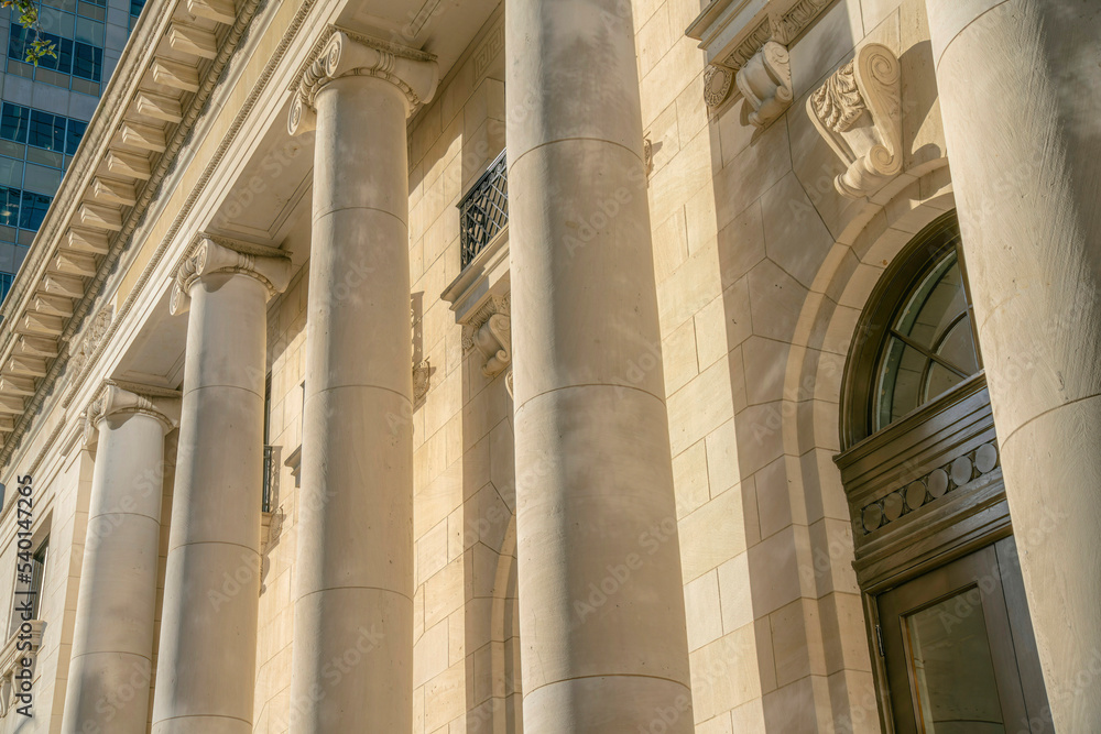 Exterior of a building with huge circular columns and brown wooden door Exterior of a building with huge circular columns and brown wooden door