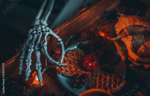 Skeleton's hand reaching for breakfast in a tray on the bedside table.