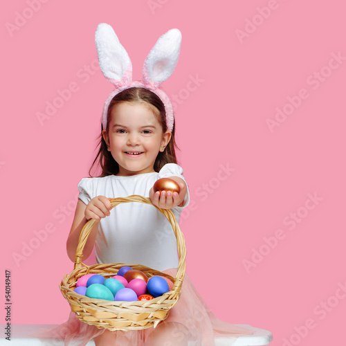 Girl wearing bunny ears headband presenting the golden Easter egg