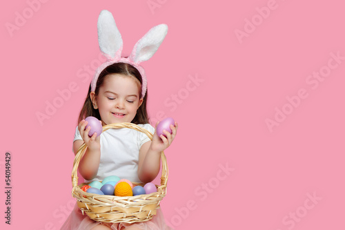 Happy little girl looking at pink Easter eggs in her hands