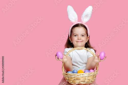 Little girl holding pink Easter eggs in her hands isolated on pink