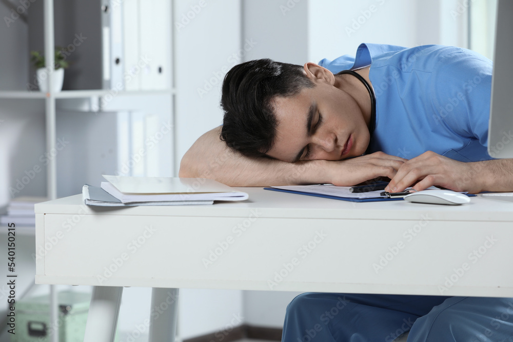 Obraz premium Exhausted doctor sleeping at workplace in hospital