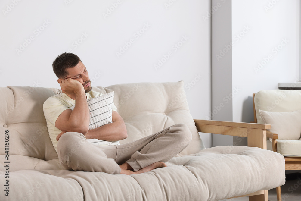 Sleepless man hugging pillow on sofa at home Sleepless man hugging pillow on sofa at home