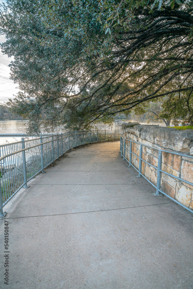 Paved pathway in Austin Texas along a river and under a canopy of trees