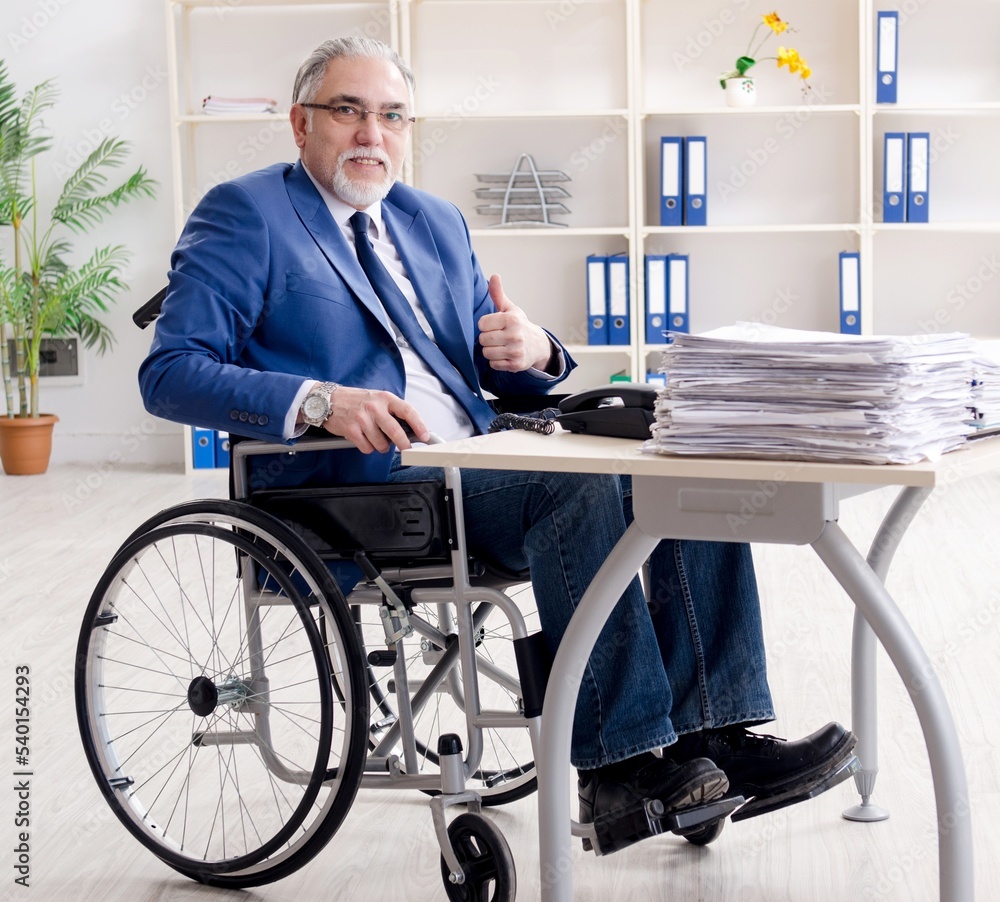 Aged employee in wheelchair working in the office Aged employee in wheelchair working in the office