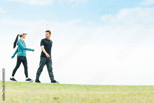 健康のため公園でウォーキング・散歩・有酸素運動するスポーツウェアを着た男女 