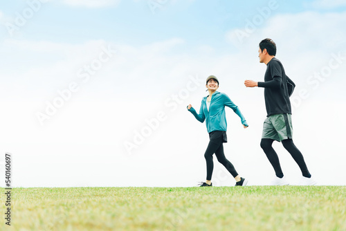 公園で話しながらランニング・ジョギング・トレーニングするスポーツウェアを着たアジア人の男女（話す） 