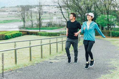 健康のため朝公園でランニング・ジョギング・有酸素運動するスポーツウェアを着たアジア人の男女 