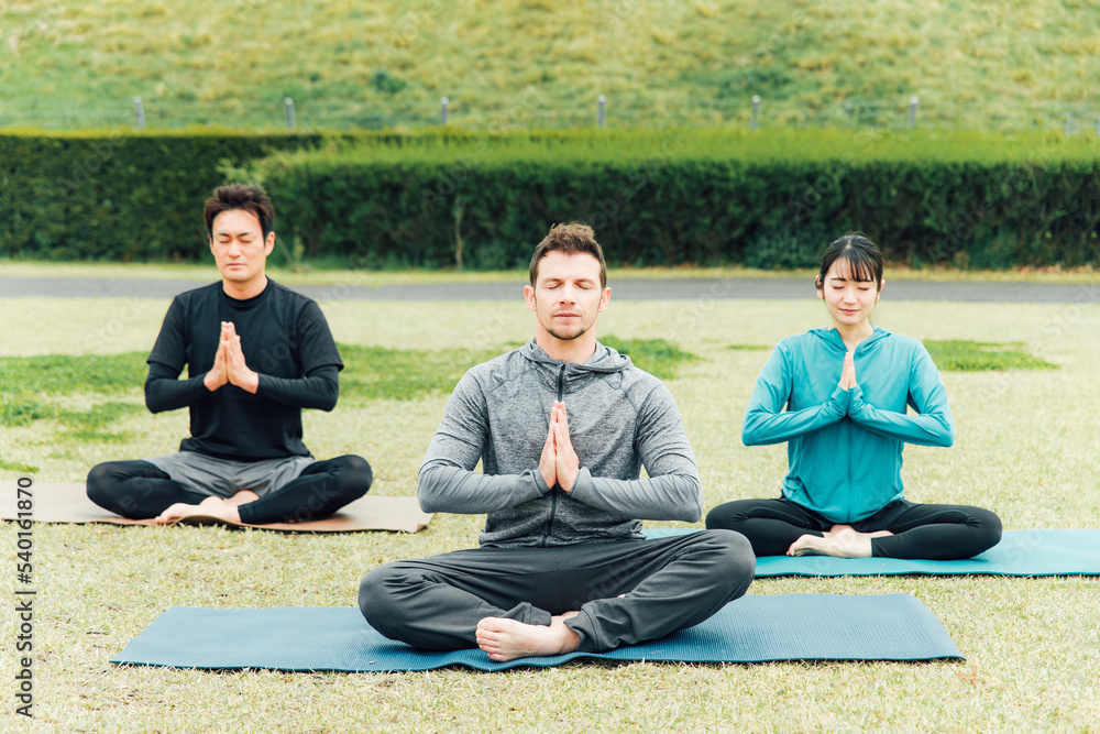 公園でヨガ・瞑想・マインドフルネスをするスポーツウェアの男女（プライベートレッスン）
