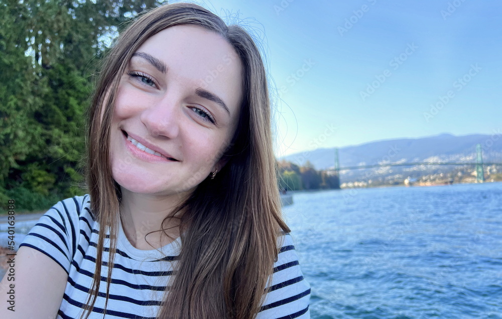 young girl of 25 years old sits and is surprised, she opened her mouth wide and her eyes are loose she has loose light brown hair she is wearing a striped sea T-shirt backdrop of Stanley Park oceans young girl of 25 years old sits and is surprised, she opened her mouth wide and her eyes are loose she has loose light brown hair she is wearing a striped sea T-shirt backdrop of Stanley Park oceans