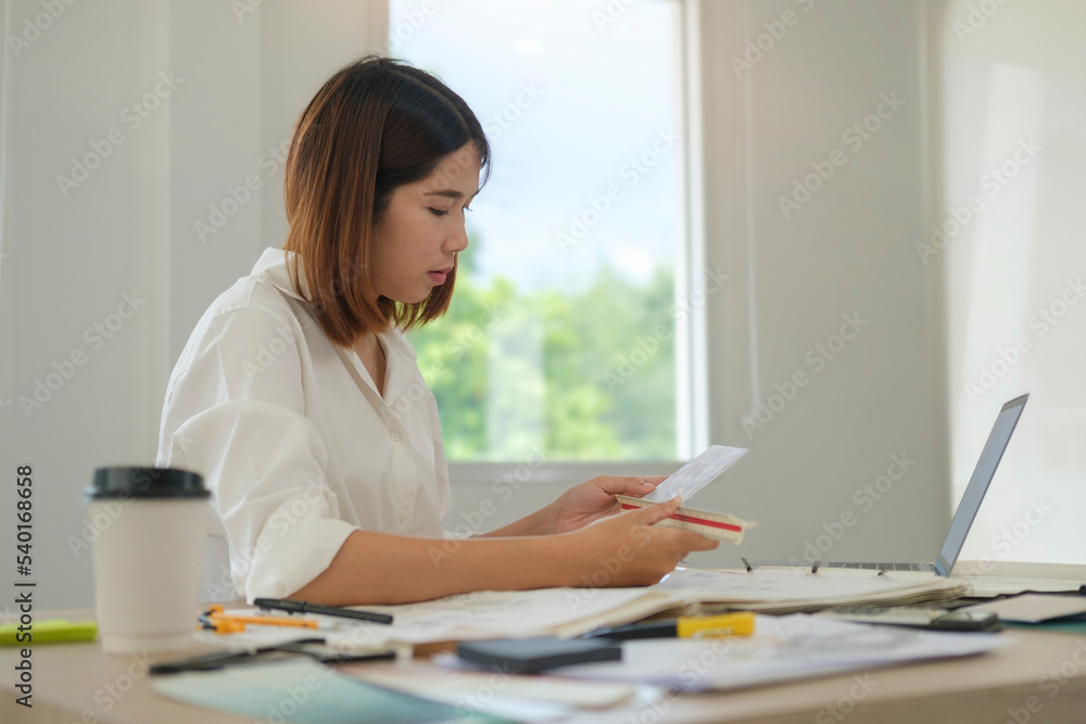 Side view of young female interior designer working on freelance renovation project at home office. Side view of young female interior designer working on freelance renovation project at home office.