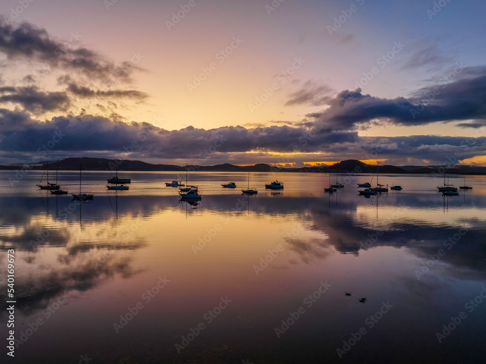 Aerial sunrise waterscape with boats, rain clouds and reflections