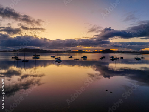 Aerial sunrise waterscape with boats  rain clouds and reflections