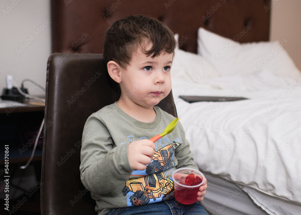 adorable young boy eating a snack and watching TV in a hotel room Stock ...