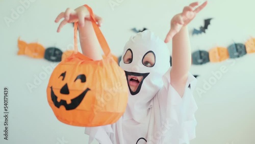 Little girl in a ghost costume scares and plays in horror stories. 4k. Halloween kid at home.