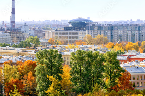 Autumn trees in urban area. The roofs of residential and industrial buildings are buried in the crowns of multi-colored foliage. © Alex Chebak
