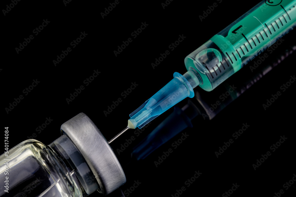 close up of glass medicine vial with syringe and needle isolated on black background. flu vaccine, doping in sport or botox hualuronic collagen, drug addicted close up of glass medicine vial with syringe and needle isolated on black background. flu vaccine, doping in sport or botox hualuronic collagen, drug addicted