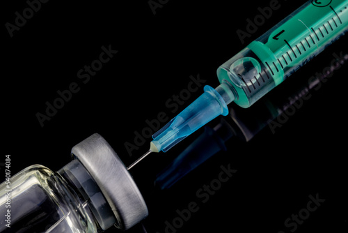 close up of glass medicine vial with syringe and needle isolated on black background. flu vaccine, doping in sport or botox hualuronic collagen, drug addicted