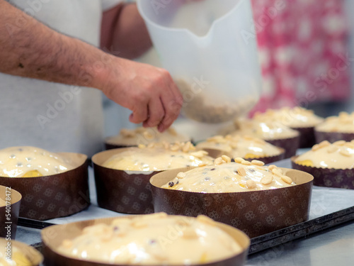 artisan italian baker preparing panettone christmas cake adding almonds to icing