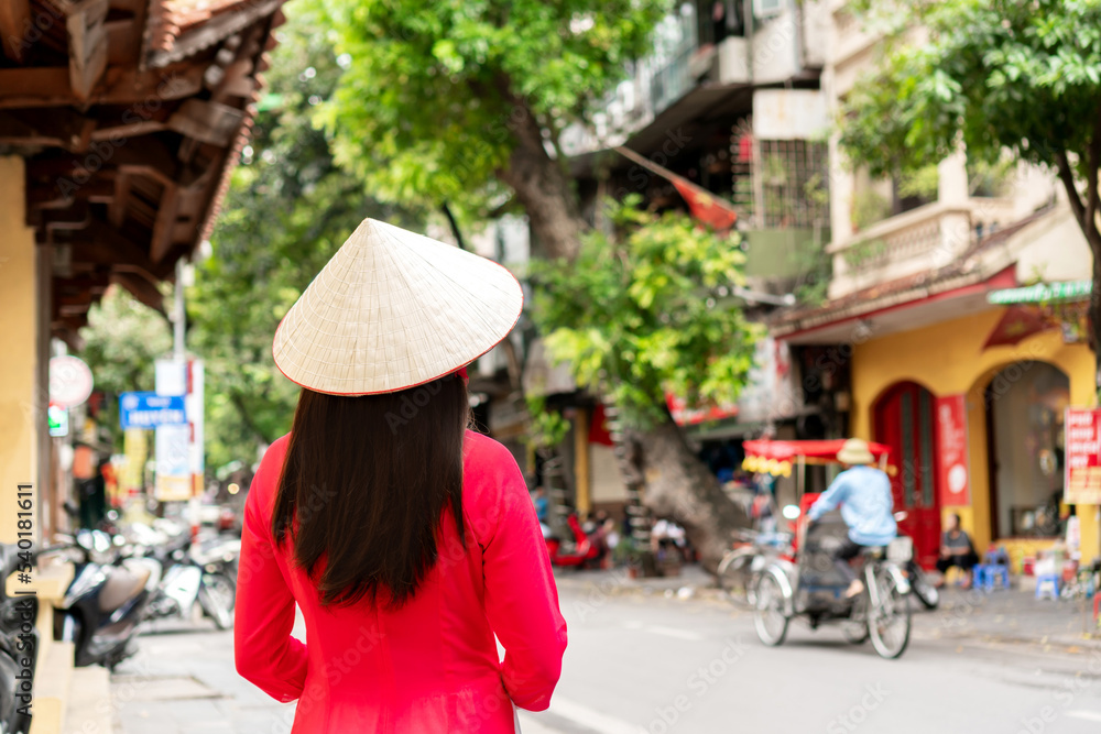 Asian tourist female is wearing Non La (traditional Vietnamese hat) and Ao Dai (traditional Vietnamese dress) enjoy sightseeing in Hanoi city Vietnam. Copy space