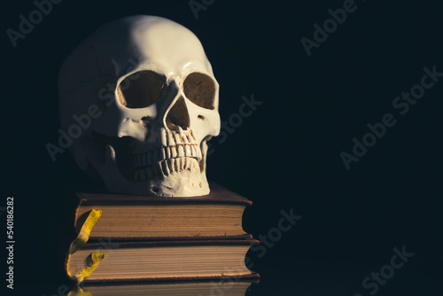 Human skull on vinatge books isolated on black background.