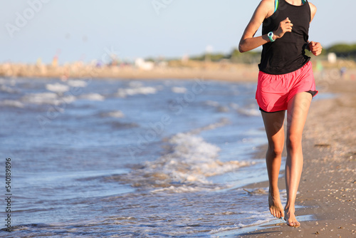 athletic girl running on the beach by the sea to train