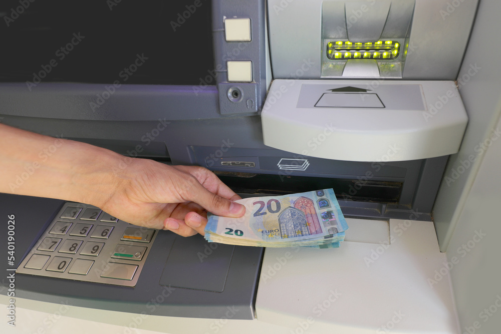 Hand picking up European € 20 banknotes from the bank ATM Hand picking up European € 20 banknotes from the bank ATM