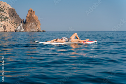 Sporty girl on a glanders surfboard in the sea on a sunny summer day. Summer activities by the sea