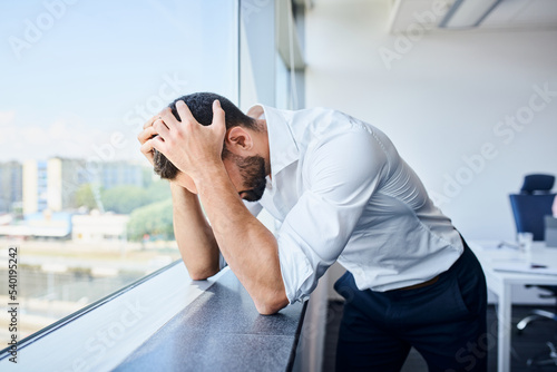 Broken businessman holding head in hands at office. Business failure concept