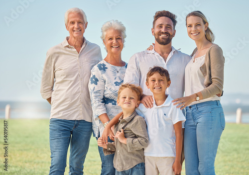 Happy, big family and nature park vacation together with grandparents in retirement, children and parents smile. Summer holiday, relax outdoors and portrait of generations love bonding field of grass