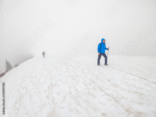 Adventurous athletic male hikers, hiking up a snow covered trail in the winter on a cloudy day in the Pacific Northwest.