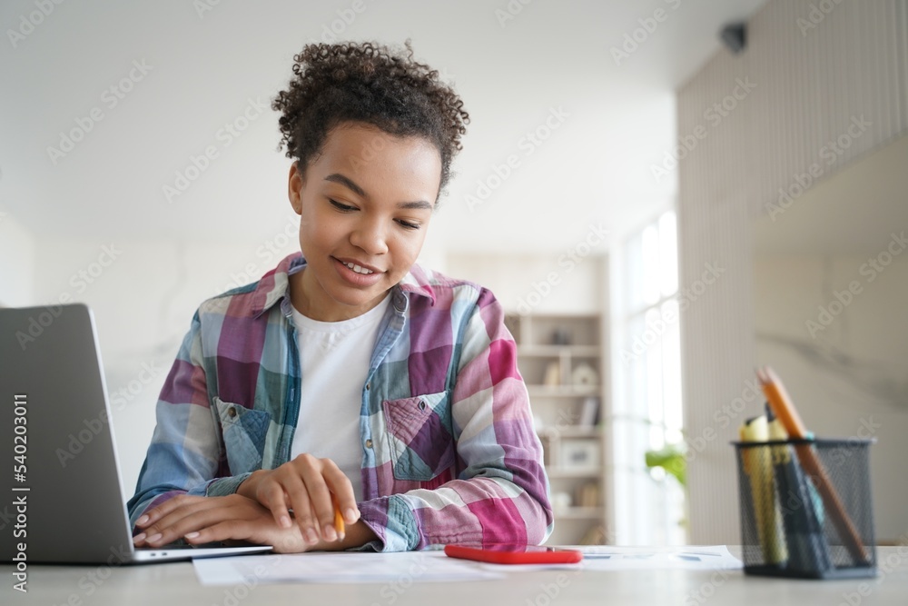 Mixed race teen girl student study sitting at desk with laptop doing homework. Distance education Mixed race teen girl student study sitting at desk with laptop doing homework. Distance education