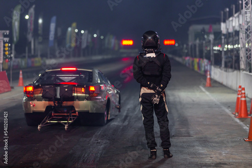 Dragster driver with drag car in race track at night, Drag racing car at the start competition at night, Drag race car in race track at night, Sport car at the start, speed competition, drag racing. photo