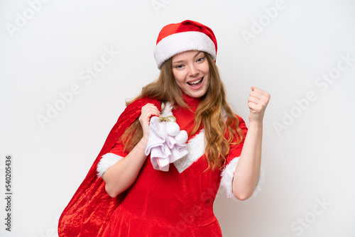 Young caucasian woman with Christmas dress holding Christmas sack isolated on white background celebrating a victory