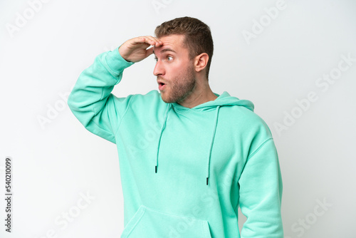 Young handsome caucasian man isolated on white background with surprise expression while looking side