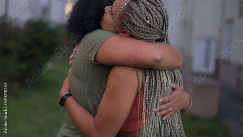Two happy Brazilian black women laughing and smiling together. Fun adult girls embrace standing outdoors. Friendship concept