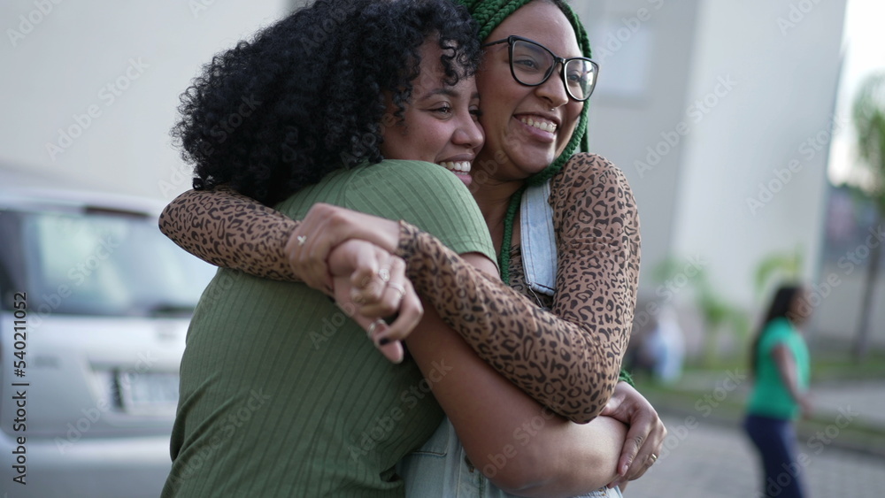 Two happy Brazilian black women laughing and smiling together. Fun adult girls embrace standing outdoors. Friendship concept Two happy Brazilian black women laughing and smiling together. Fun adult girls embrace standing outdoors. Friendship concept