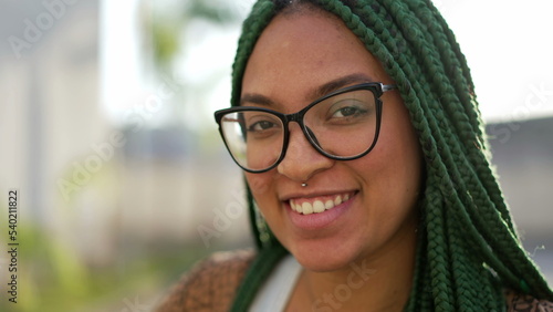 Portrait of a young black woman face smiling at camera. South American Brazilian adult girl standing outdoors. Millennial generation with box braid hairstyle photo