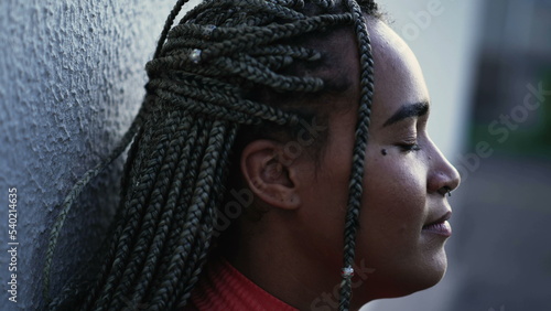 Meditative young woman eyes closed relaxing outside. A pensive hispanic black Brazilian with restul peace of mind photo