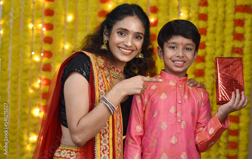 Happy young woman and son celebrating diwali holding plate of diyas,gift boxes © Karan