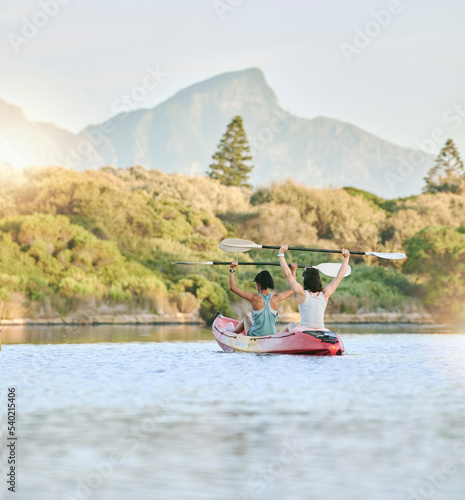 Woman friends, celebrate in kayak and lake exercise in a canoe together training for summer body fitness. Female rowing, paddle on river and women workout water sport race activity on nature vacation