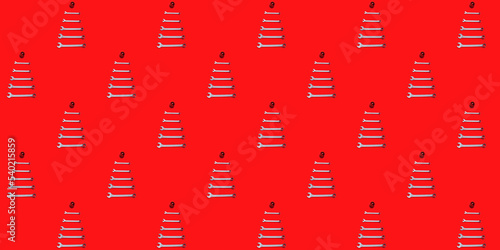 Seamless texture with Christmas trees made of wrenches decorated with balls on a red background. Happy New Year pattern. Banner with tools. Wallpaper. Industrial holiday concept. Calendar template