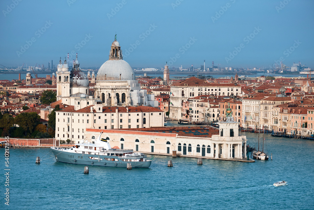 Aerial view of Punta Dogana with Santa Maria della Salute. Bird view of blue water of Venetian lagoon and Grand Canal. Bright day with blue sky and sea.
