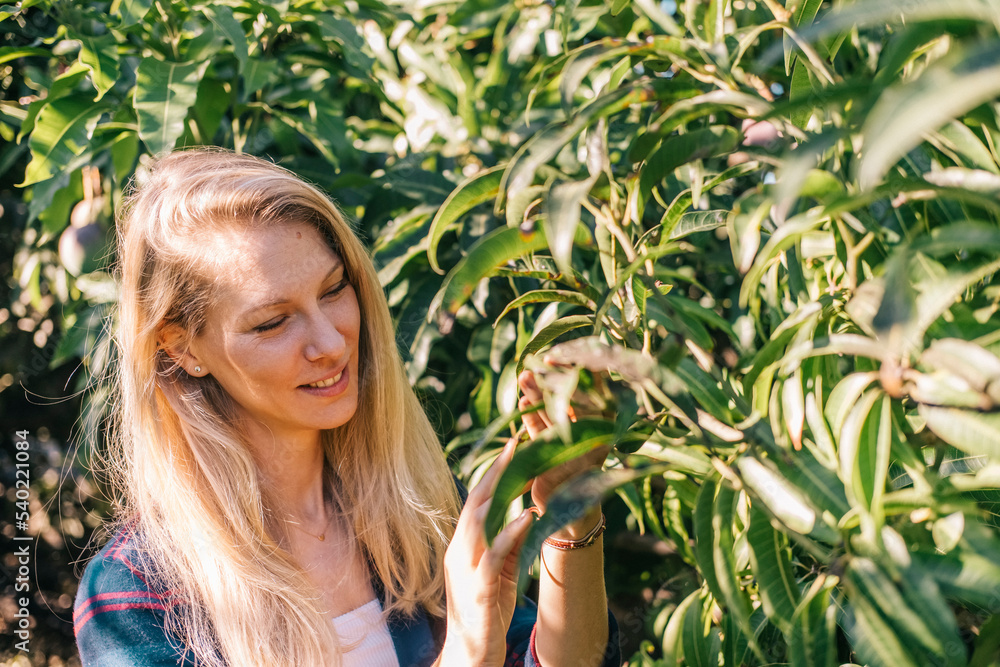 Beautiful and young caucasian woman taking care of the plants in a garden Beautiful and young caucasian woman taking care of the plants in a garden