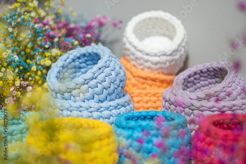close-up of a beautiful colorful crochet baskets on colorful flower background. Handicraft advertising.  a nice hobby in the winter evenings. Sustainable  organic lifestyle advertising. 