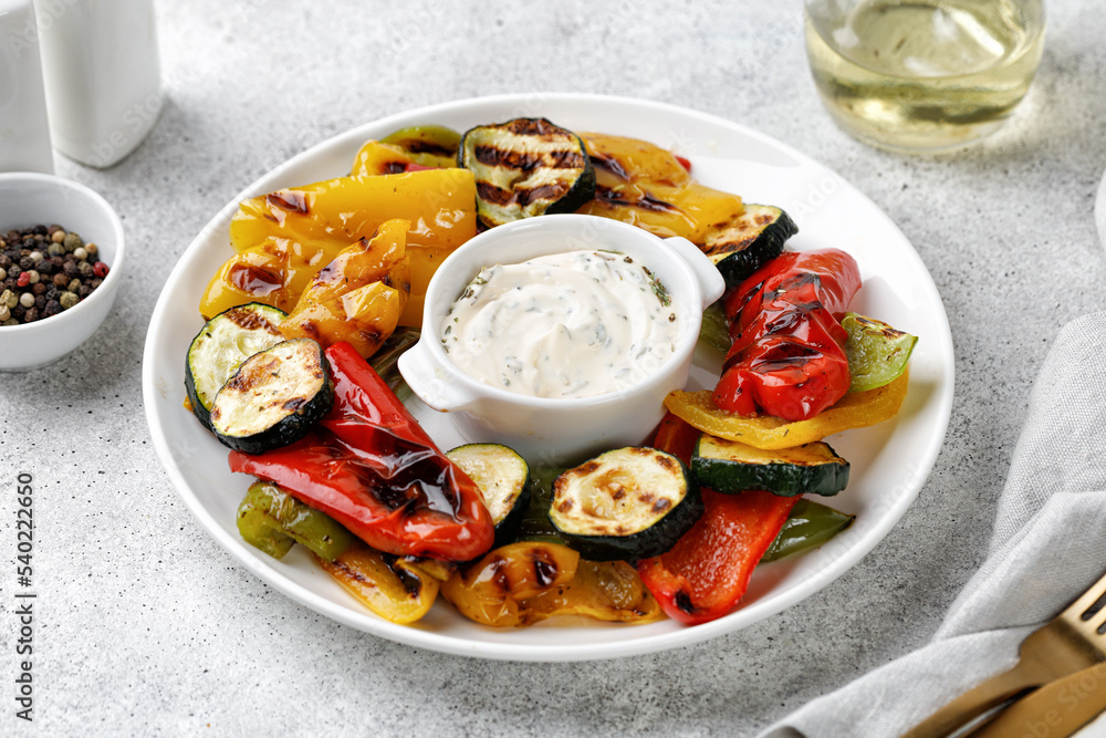 Grilled vegetable, bell sweet pepper and zucchini on a white plate and grey background. Healthy vegan food.