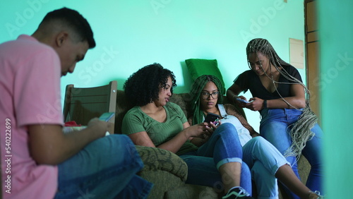 Group of friends looking cellphones at home. People using phones sitting on couch each inside their own technology bubbles