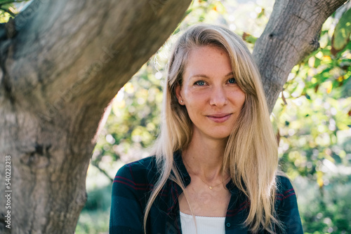 Portrait of a smiling young Caucasian woman in a natural setting.